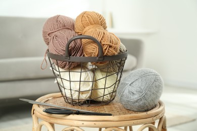 Photo of Skeins of soft yarn, knitting needles and scissors on table indoors