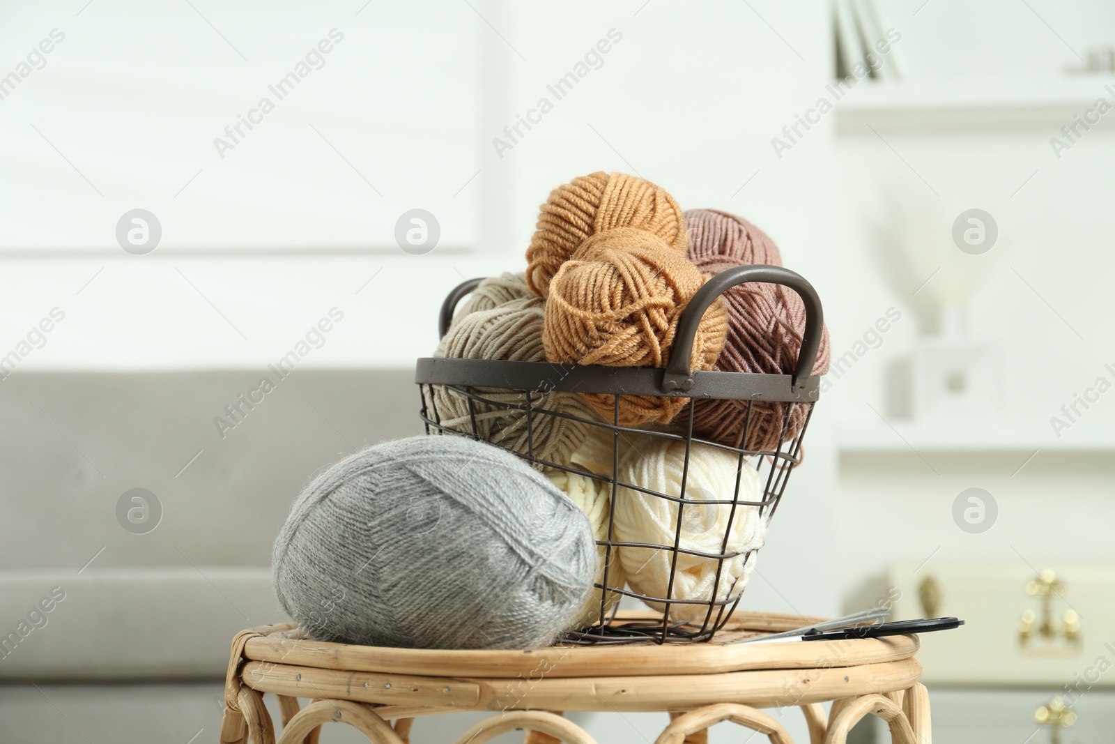 Photo of Skeins of soft yarn, knitting needles and scissors on table indoors