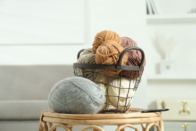 Photo of Skeins of soft yarn, knitting needles and scissors on table indoors