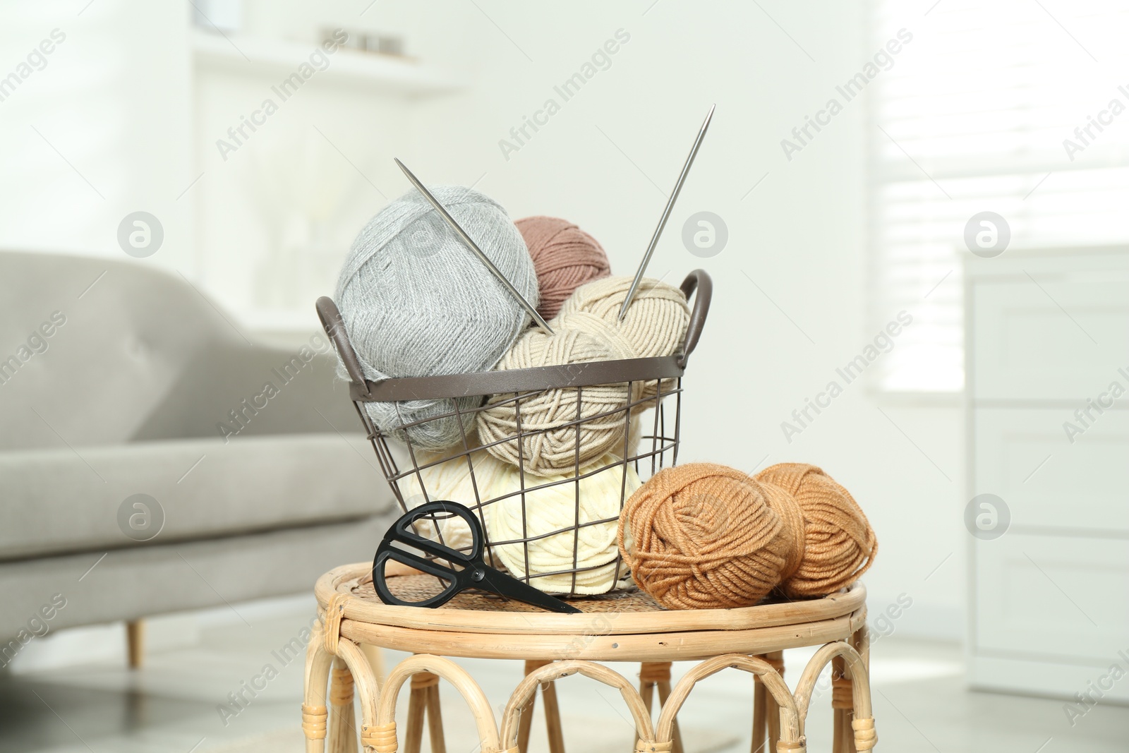 Photo of Skeins of soft yarn, knitting needles and scissors on table indoors