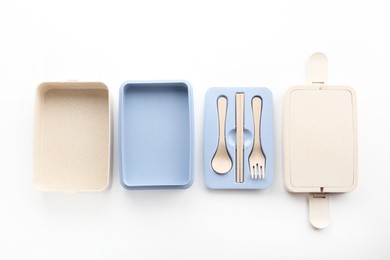 Photo of Compartments of plastic lunch box with cutlery isolated on white, top view