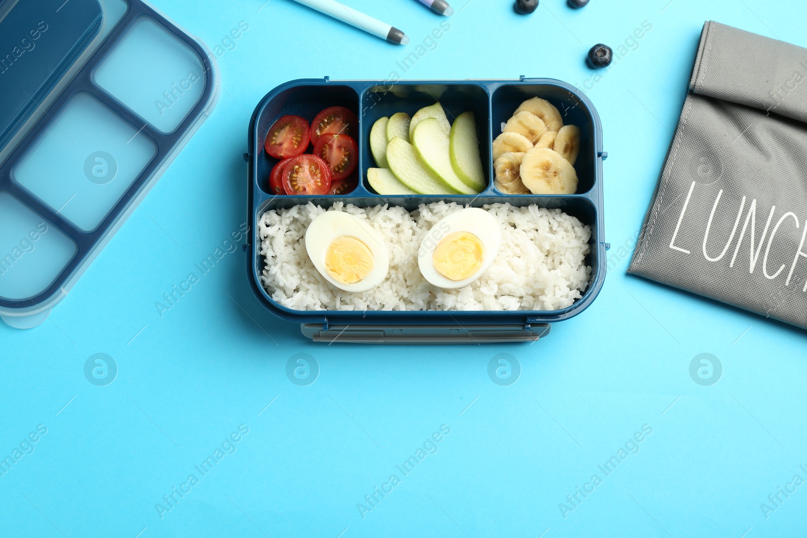 Photo of Bag and lunch box with snacks on light blue background, flat lay. Space for text