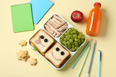 Photo of Sandwiches with smiley faces in lunch box, bottle of juice and stationery on yellow table, flat lay