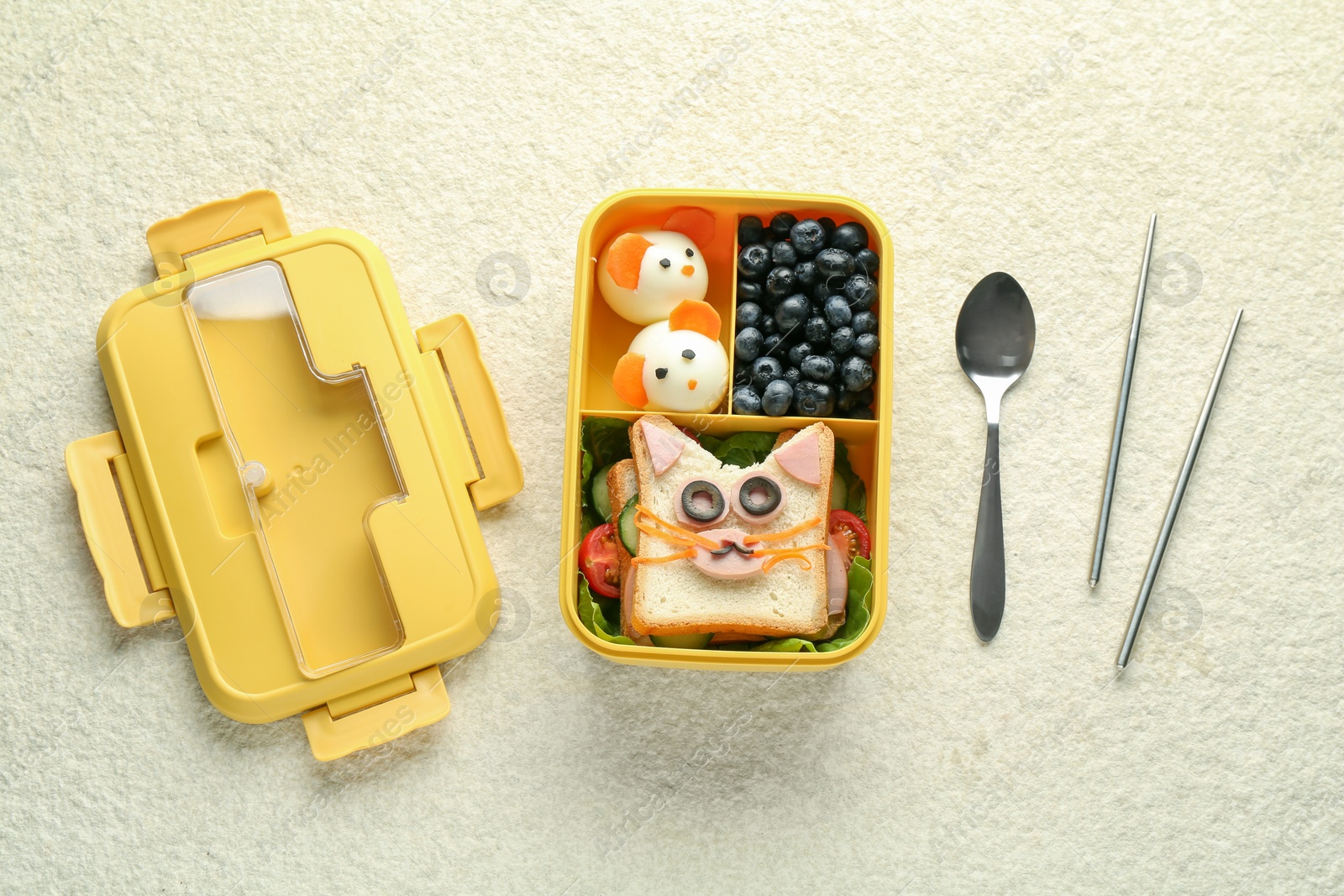 Photo of Lunch box with snacks, spoon and chopsticks on beige textured table, flat lay