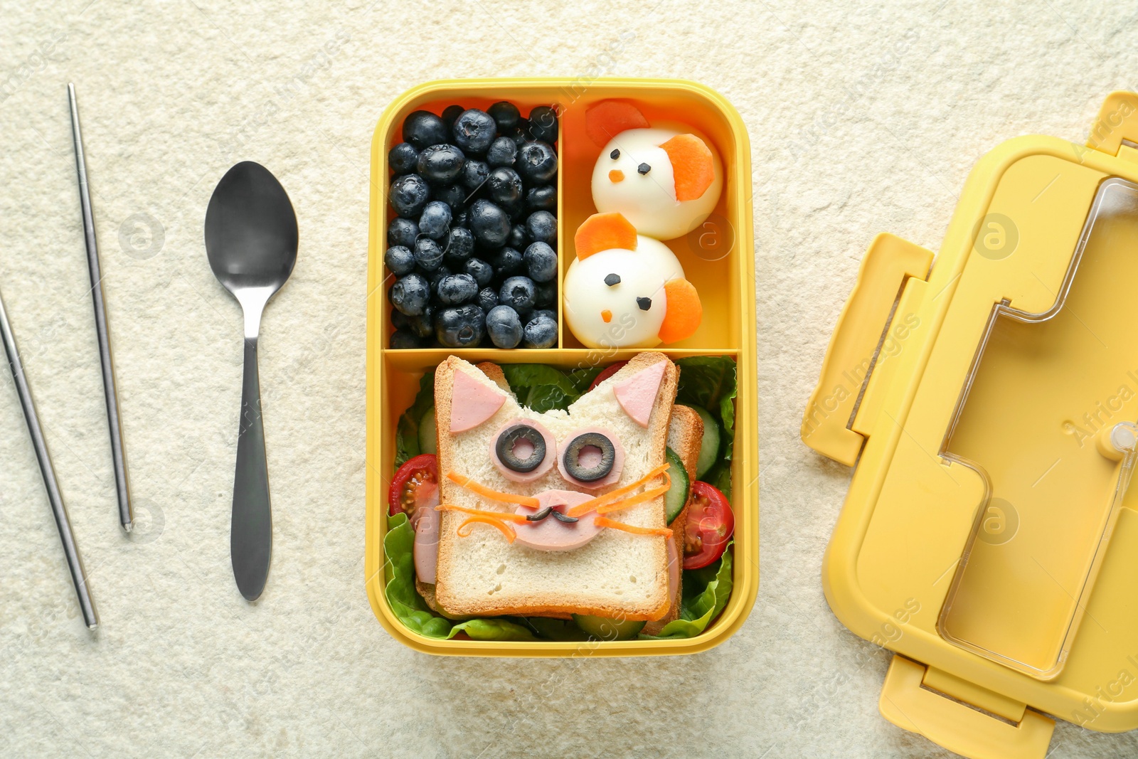 Photo of Lunch box with snacks, spoon and chopsticks on beige textured table, flat lay