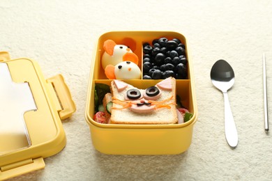 Photo of Lunch box with snacks, spoon and chopstick on beige textured table