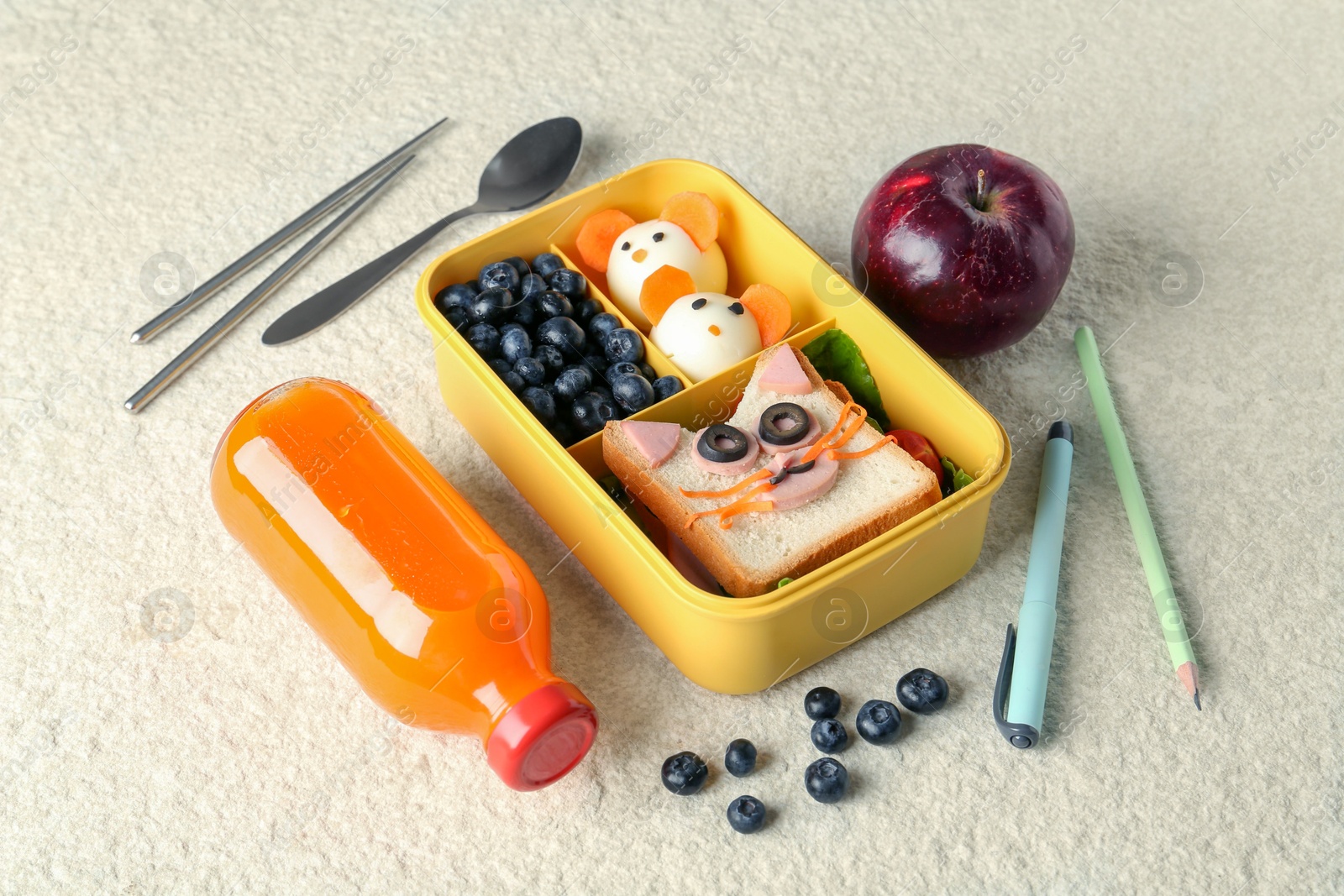 Photo of Lunch box with snacks, bottle of juice, cutlery, pen and pencil on beige textured table