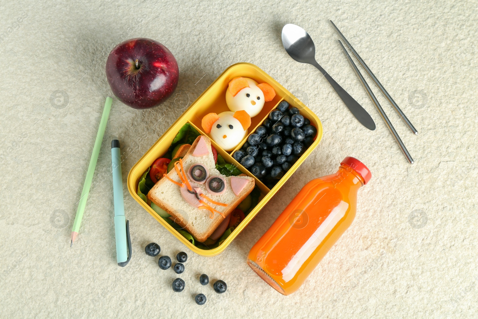 Photo of Lunch box with snacks, bottle of juice, cutlery, pen and pencil on beige textured table, flat lay