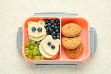 Photo of Lunch box with sandwiches, grapes, blueberries and cookies on beige textured table, top view