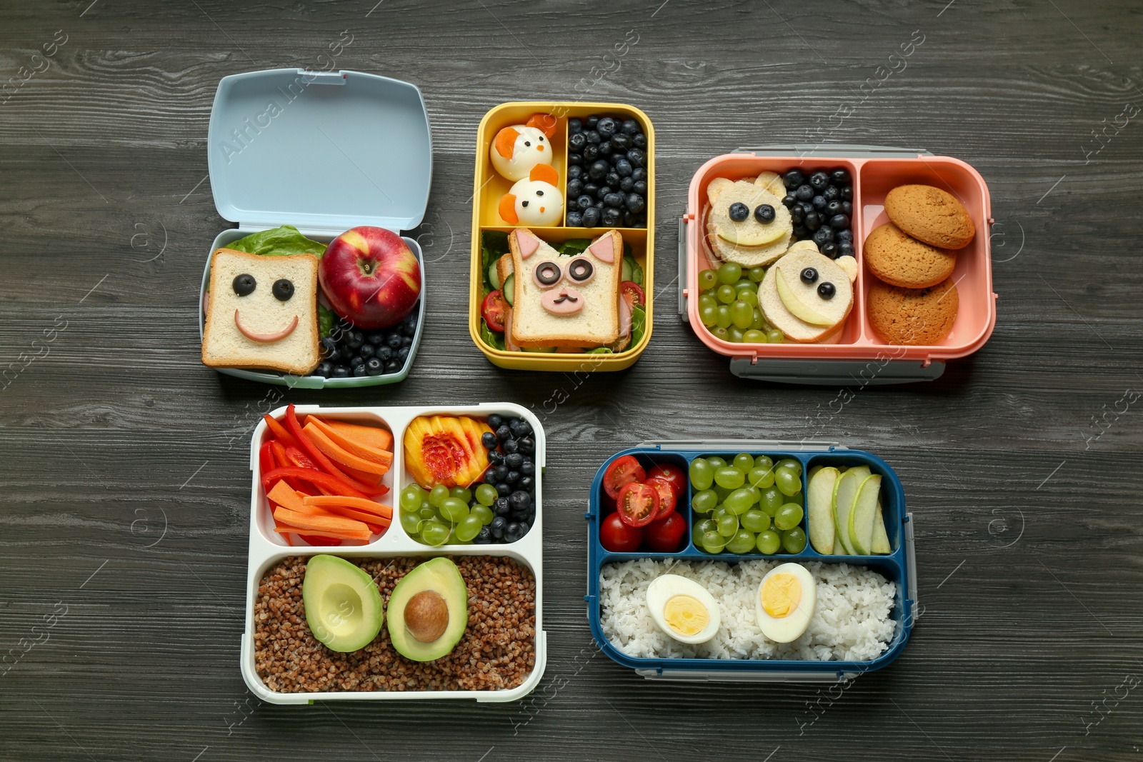 Photo of Lunch boxes with different snacks on wooden table, flat lay