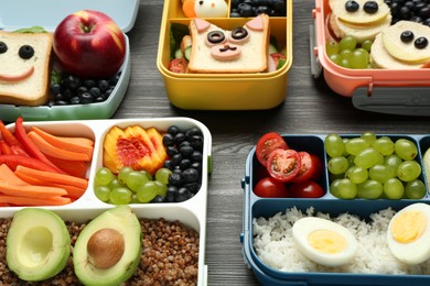 Photo of Lunch boxes with different snacks on wooden table, closeup