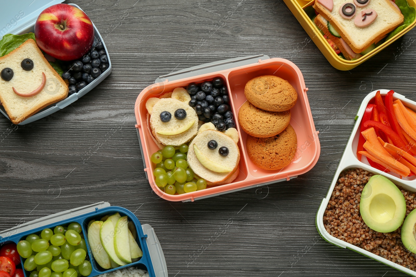 Photo of Lunch boxes with different snacks on wooden table, flat lay