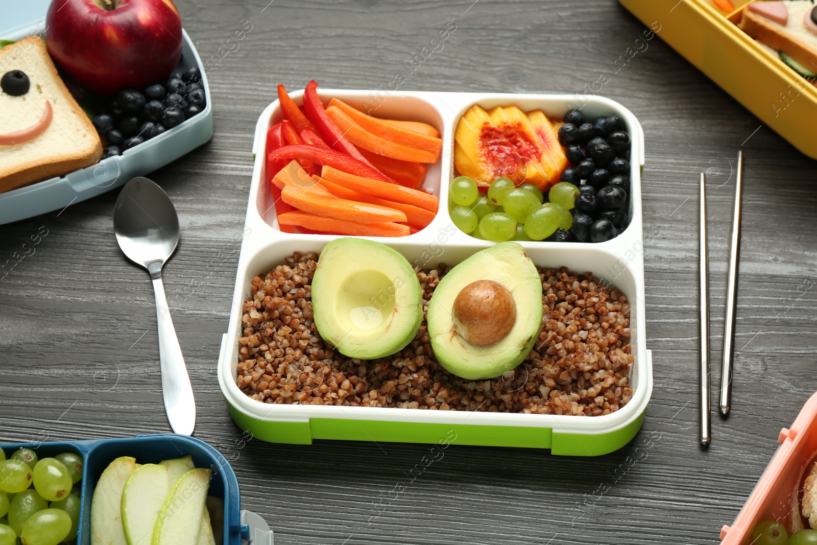 Photo of Lunch boxes with different snacks and cutlery on wooden table, above view