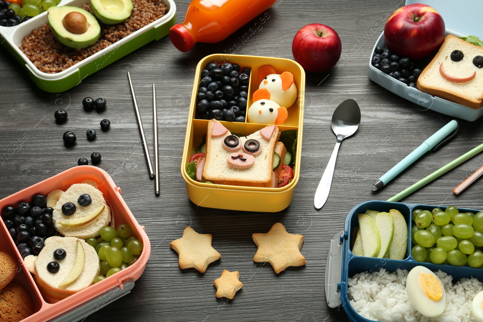 Photo of Lunch boxes with different snacks, bottle of juice and cutlery on wooden table, above view