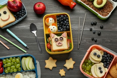 Photo of Lunch boxes with different snacks, bottle of juice and cutlery on wooden table, flat lay