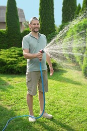 Man watering lawn with hose in backyard