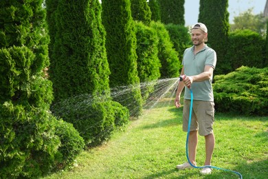 Photo of Man watering lawn with hose in backyard