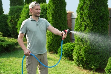 Man watering lawn with hose in backyard