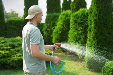 Man watering lawn with hose in backyard