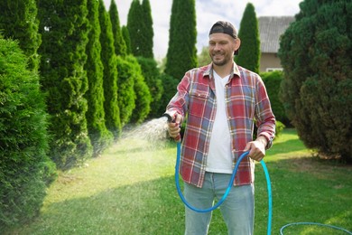 Man watering lawn with hose in backyard