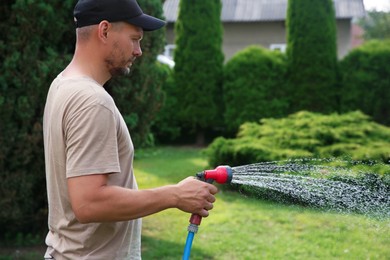 Man watering lawn with hose in backyard