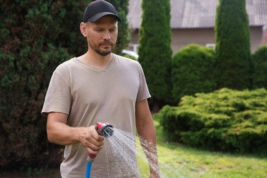 Man watering lawn with hose in backyard