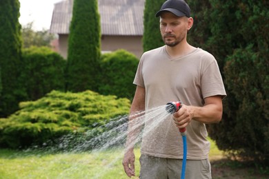 Photo of Man watering lawn with hose in backyard