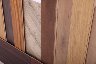 Photo of Many different samples of wooden flooring as background, closeup