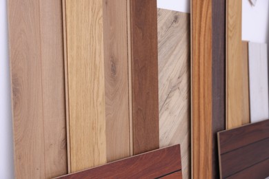 Photo of Many different samples of wooden flooring on light background