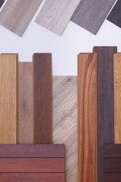 Photo of Many different samples of wooden flooring on light background