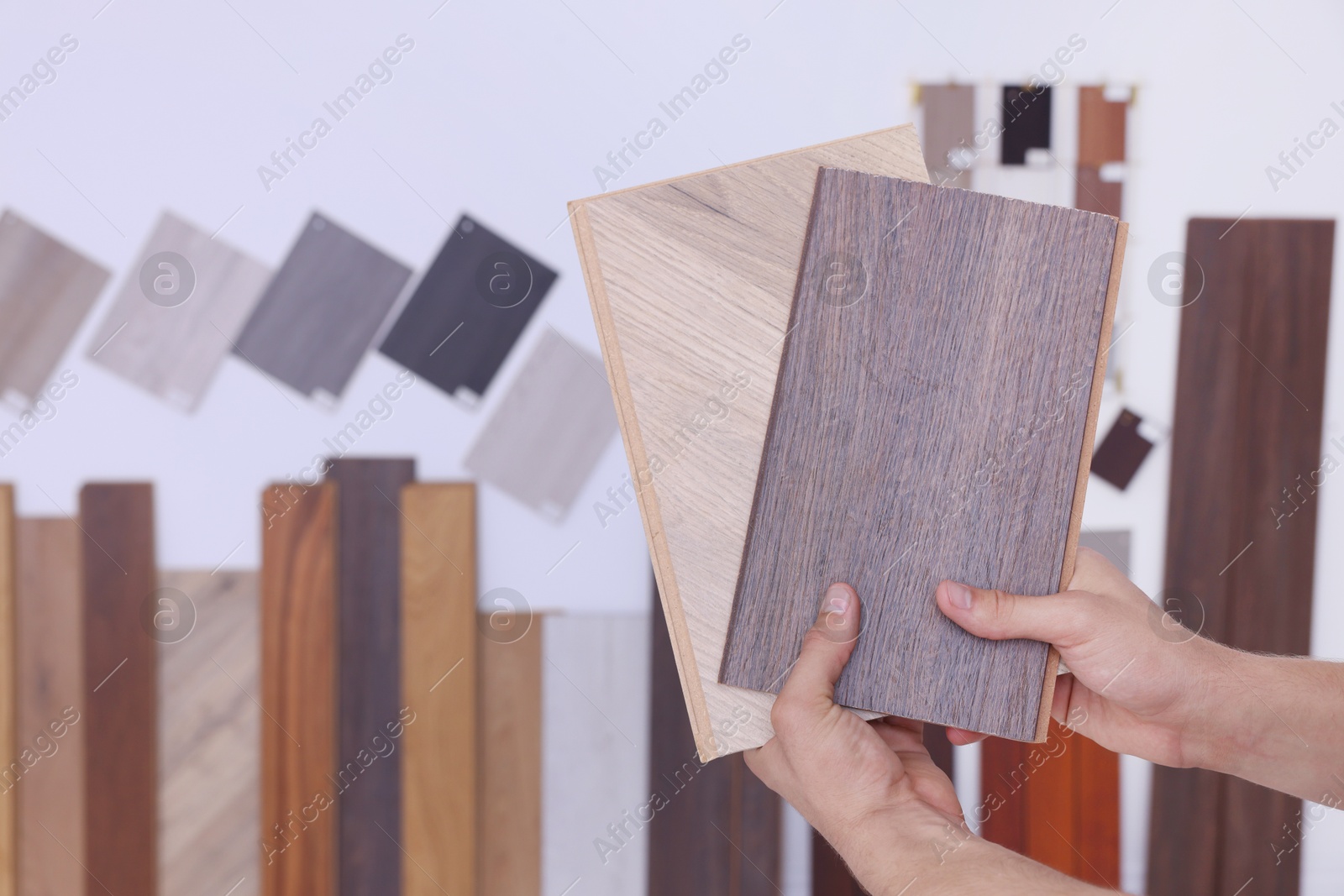 Photo of Man with different samples of wooden flooring indoors, closeup