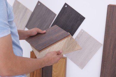 Photo of Man with different samples of wooden flooring indoors, closeup