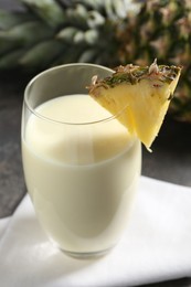 Photo of Tasty pineapple smoothie in glass and fresh fruit on table, closeup