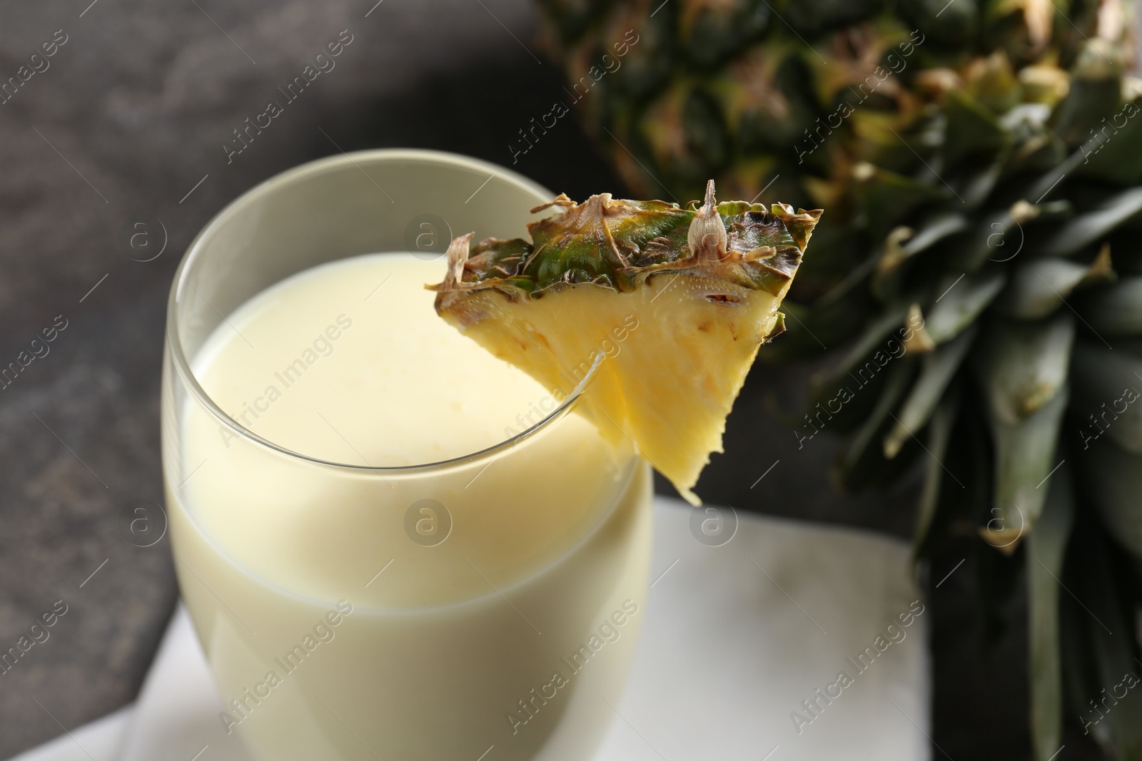 Photo of Tasty pineapple smoothie in glass and fresh fruit on table, closeup