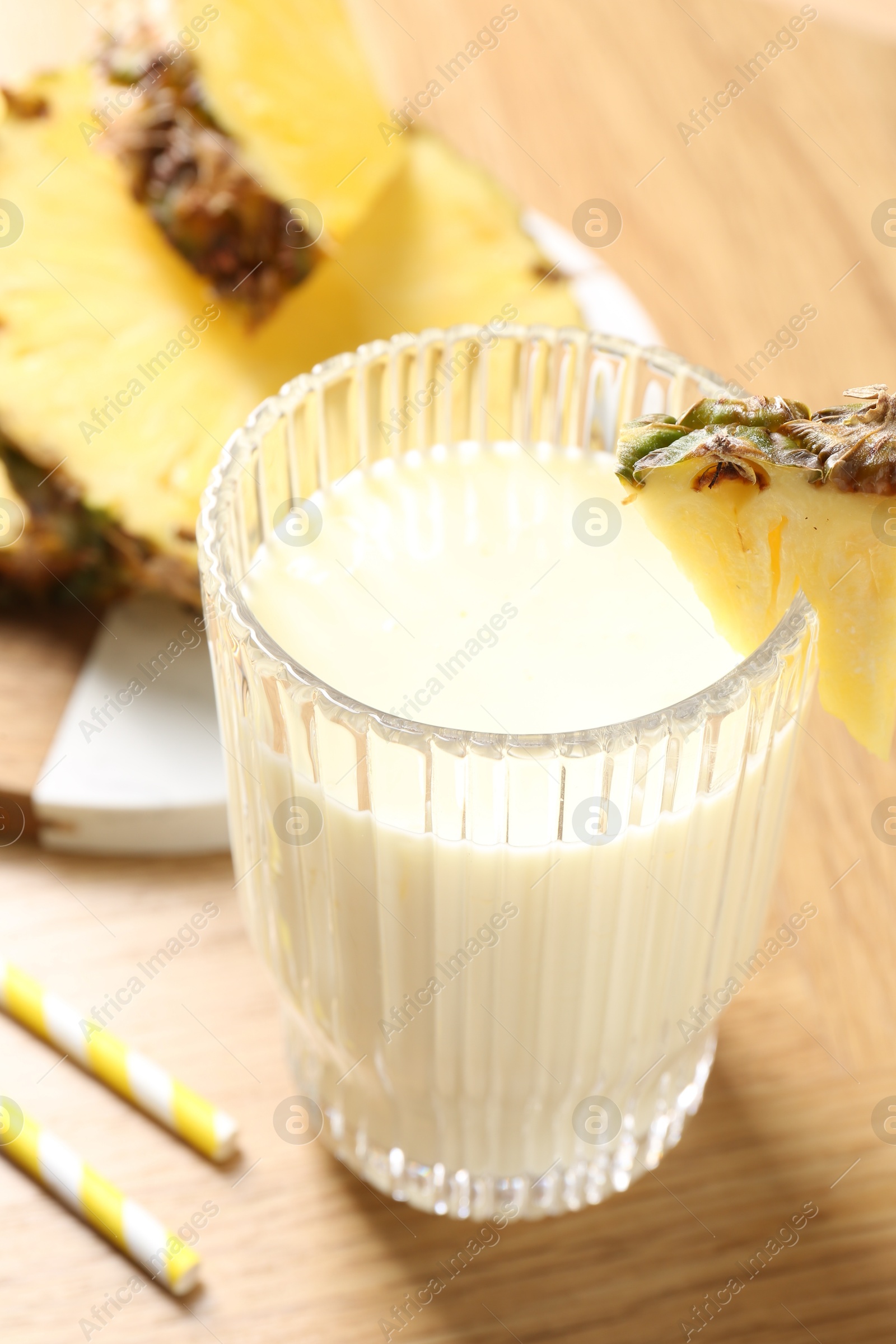 Photo of Tasty pineapple smoothie in glass and fresh fruit on wooden table, closeup