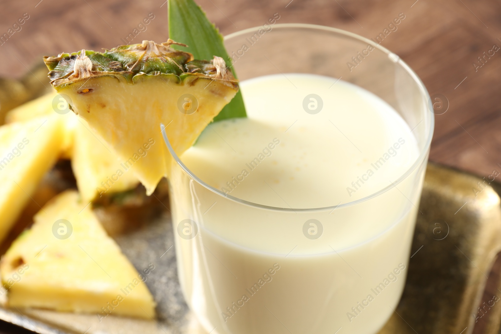 Photo of Tasty pineapple smoothie in glass and fresh fruit on table, closeup