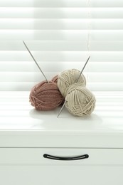 Photo of Soft yarn and knitting needles on chest of drawers indoors