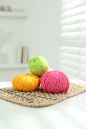 Skeins of soft yarn and knitting needles on white table indoors