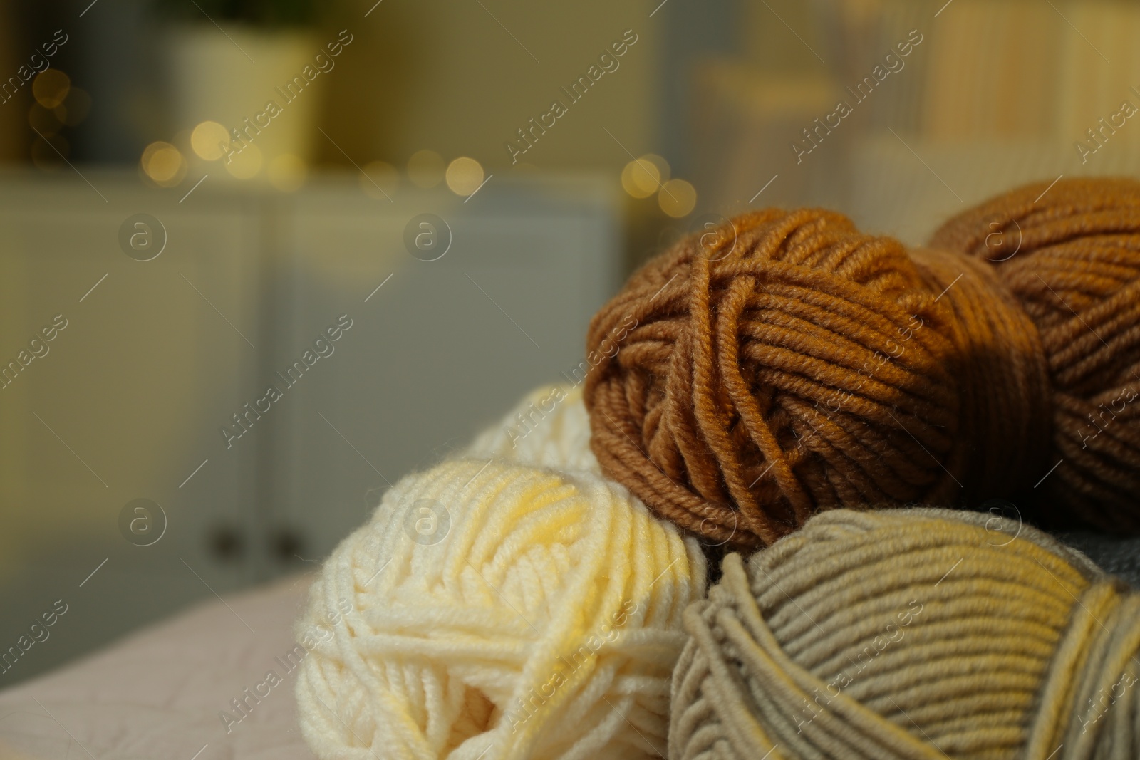 Photo of Skeins of soft yarn on bed indoors, closeup. Knitting material