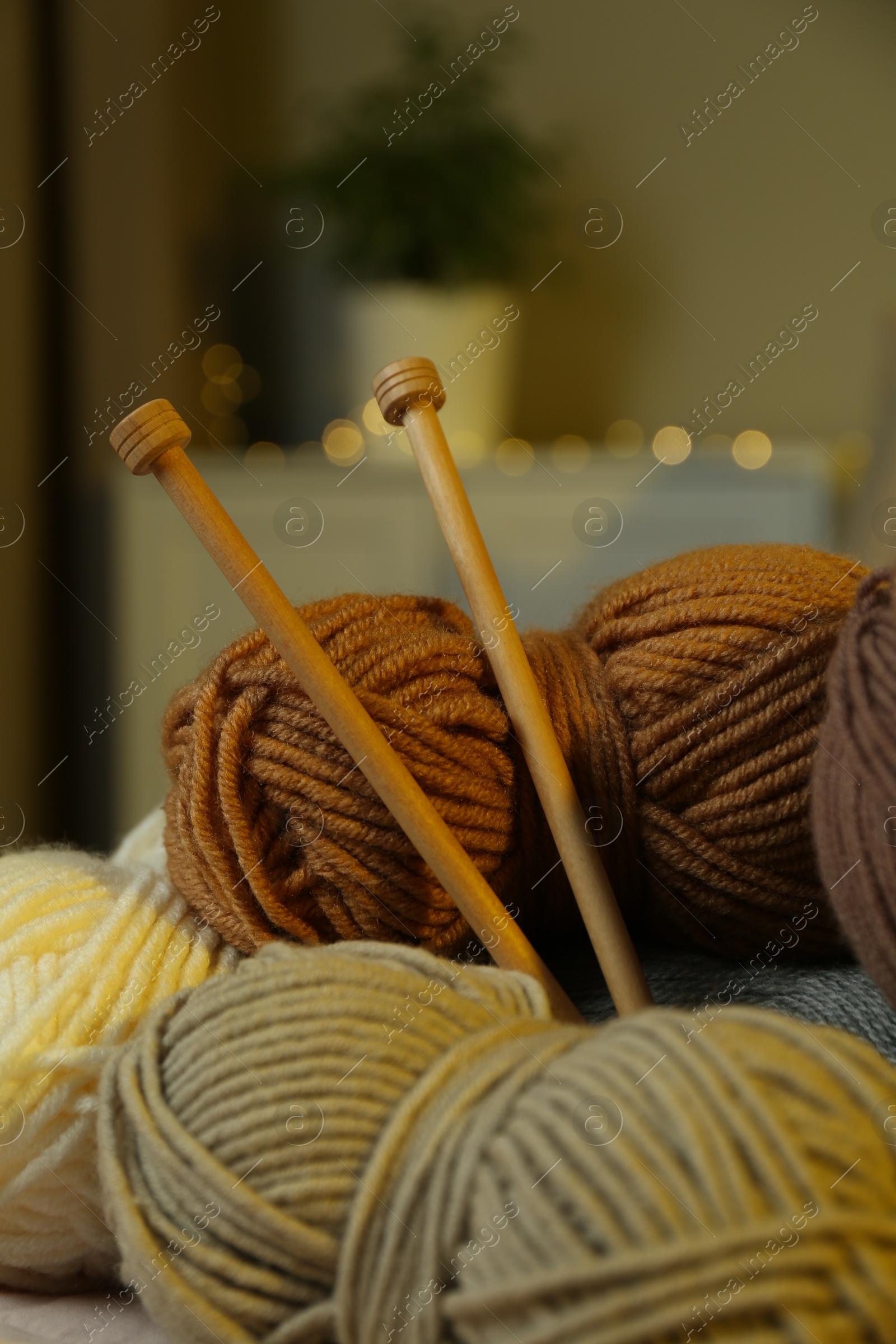 Photo of Skeins of soft yarn and knitting needles indoors, closeup