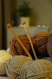 Skeins of soft yarn and knitting needles indoors, closeup