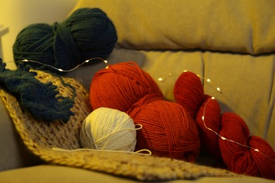 Photo of Knitting material. Skeins of soft yarn on sofa indoors