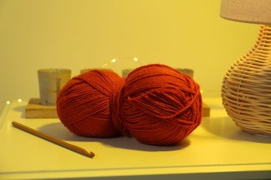 Photo of Knitting material. Skein of soft yarn and crochet hook on table indoors