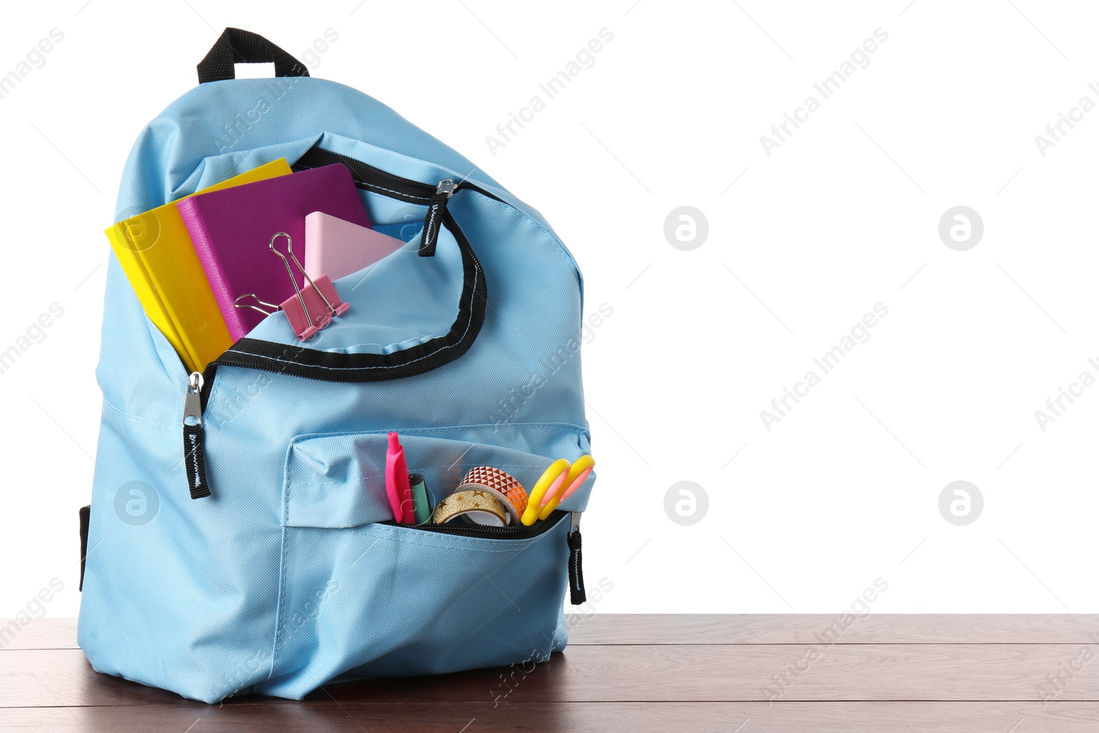 Photo of Backpack with different school stationery on wooden table against white background, space for text