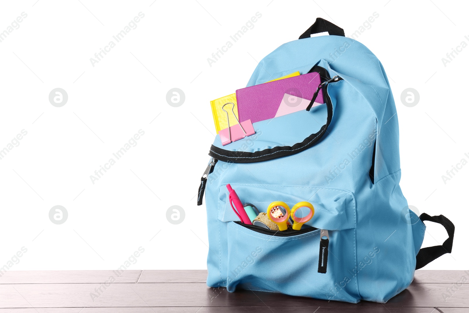 Photo of Backpack with different school stationery on wooden table against white background, space for text