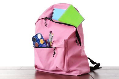 Photo of Backpack with different school stationery on wooden table against white background