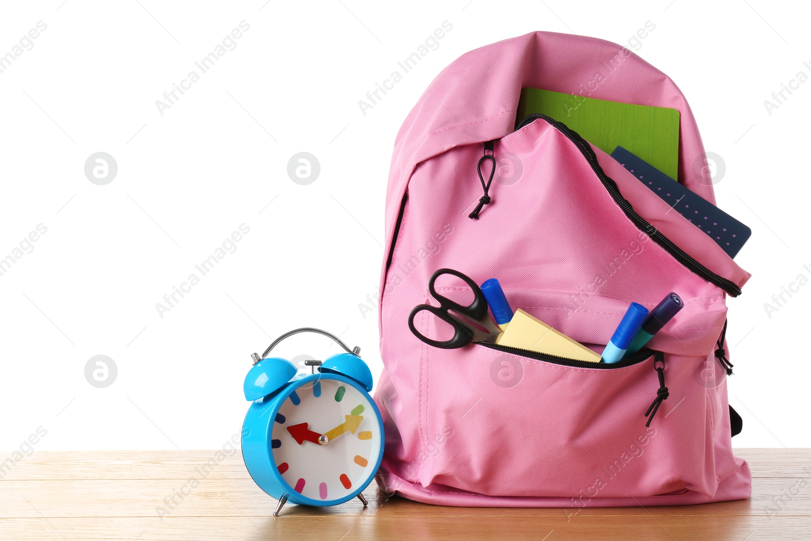 Photo of Backpack with different school stationery and alarm clock on wooden table against white background