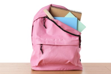 Photo of Backpack with notebooks and ruler on wooden table against white background