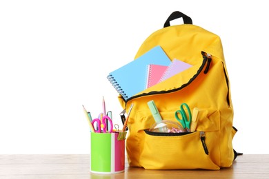 Photo of Backpack with different school stationery on wooden table against white background, space for text