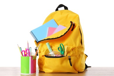 Photo of Backpack with different school stationery on wooden table against white background